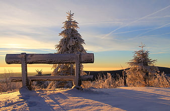 Snowy Wooden Bench on Mountain Peak at Sunset