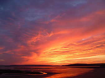 Vibrant Orange and Purple Sunset Over Calm Ocean Beach