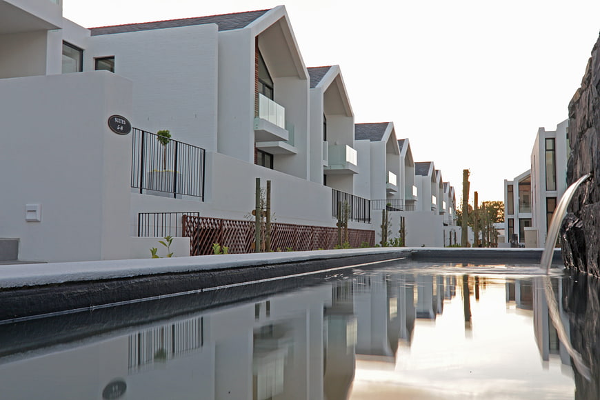 Modern white villas with pool reflection at sunset