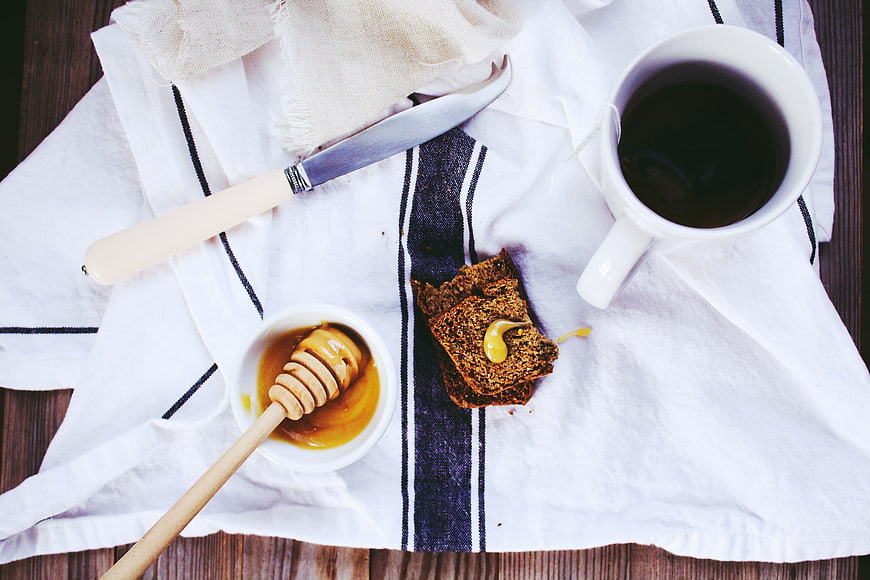 Top view of rustic breakfast with dark bread, honey, and coffee