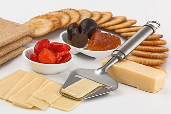 Cheese platter with crackers, sun-dried tomatoes, and cheese slicer