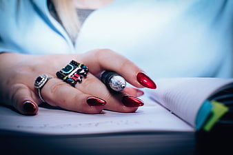 Close-up of woman's hand with red nails writing in notebook