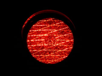 Close-up of a glowing red traffic light lens against a black background