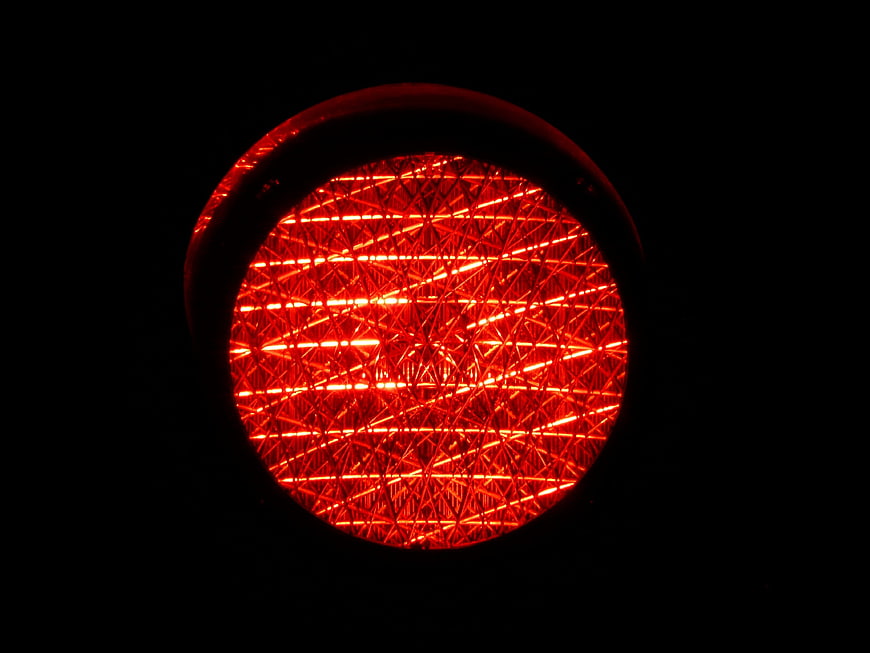 Close-up of a glowing red traffic light lens against a black background