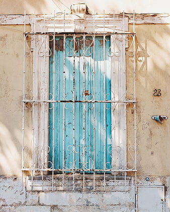 Vintage turquoise window with white iron bars on old wall
