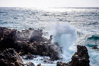 Powerful ocean waves crashing against dark rocky coastline