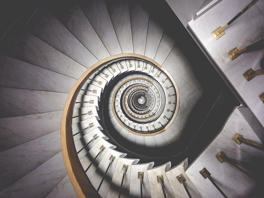 Top-down view of elegant spiral marble staircase with gold accents