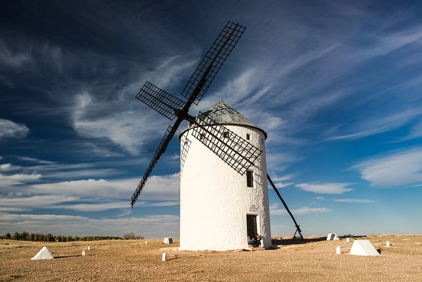 Traditional White Windmill in Arid Landscape Under Blue Sky
