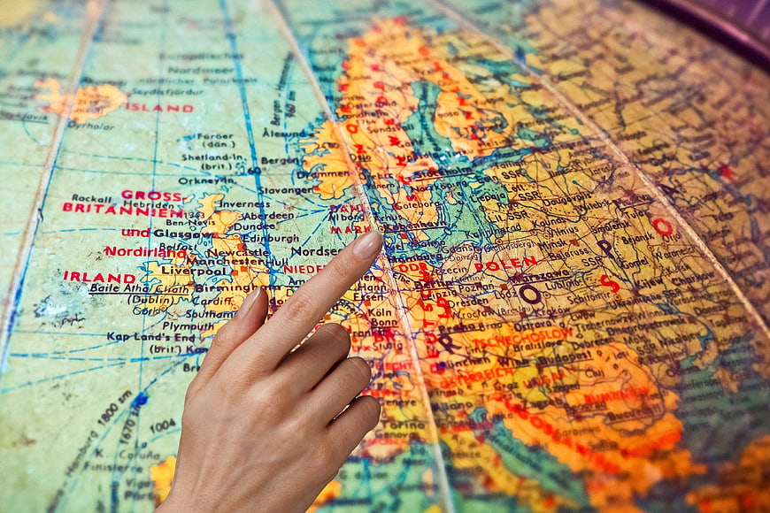Hand Pointing at Europe on Vintage World Map