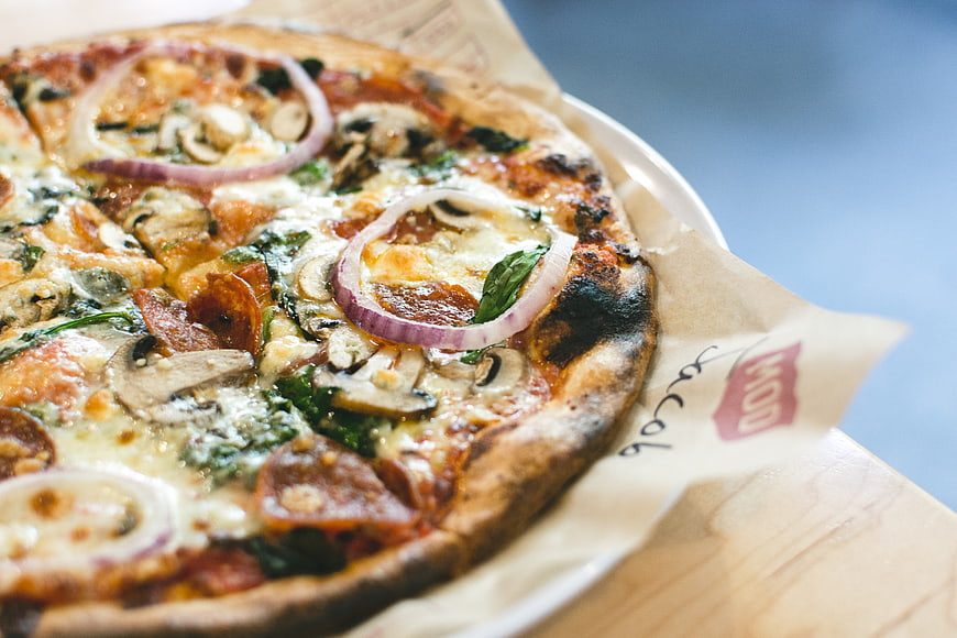 Close-up of rustic pizza with salami, mushrooms, and red onion