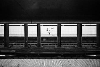 Black and white photo of a person running in a subway station