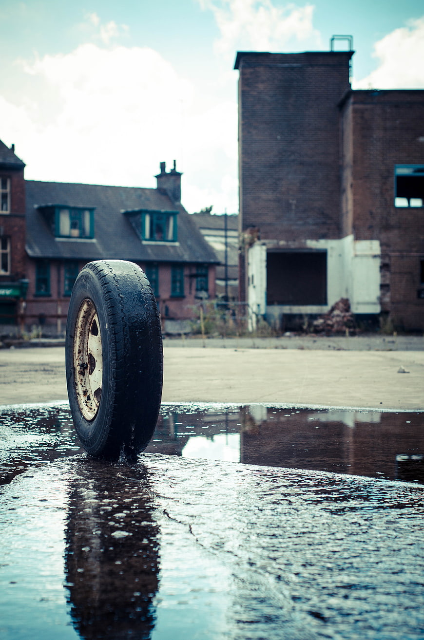 Lone tire standing in puddle with urban decay background