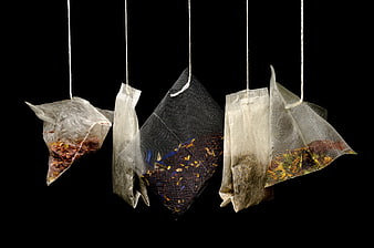 Hanging herbal tea bags on black background