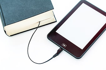 E-reader connected to book with charging cable on white background