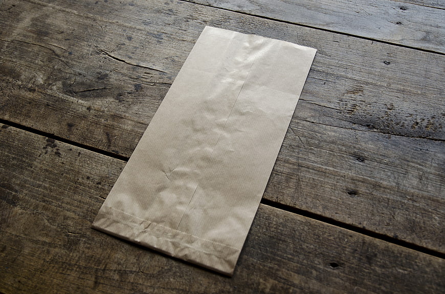 Blank Brown Paper Bag On Rustic Weathered Wooden Table Surface