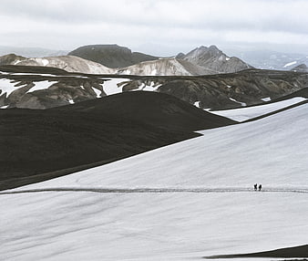 Two Hikers Walking on Snowy Mountain Slope in Iceland