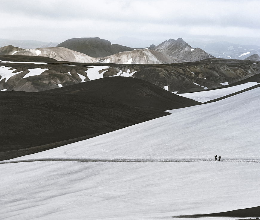 Two Hikers Walking on Snowy Mountain Slope in Iceland