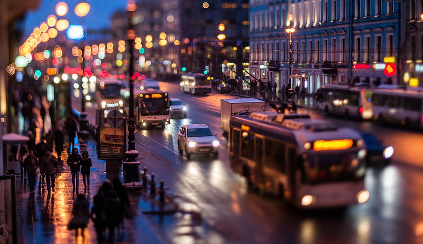 Tilt-shift city street at night with tram and traffic