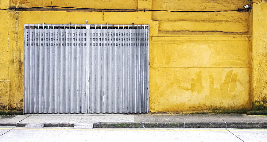 Closed metal shutter on textured yellow wall