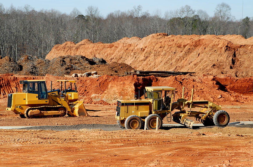 Yellow Bulldozer and Motor Grader on Red Dirt Construction Site