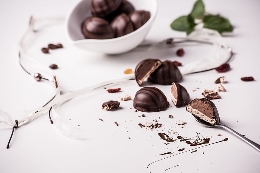 Artistic arrangement of chocolate truffles with cream drizzle on white background