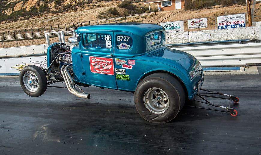 Vintage Blue Dragster Performing Wheelie on Racetrack