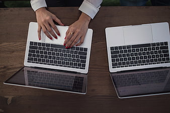 Top view of woman typing on laptop at wooden desk
