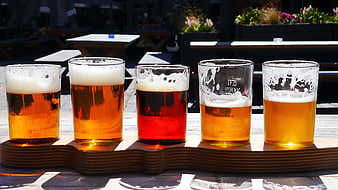 Flight of five craft beers on wooden tray outdoors