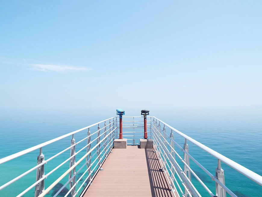 Wooden pier with binoculars overlooking turquoise ocean