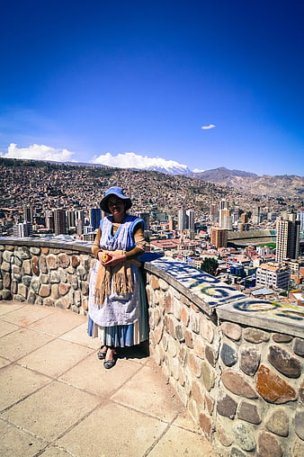 Woman in traditional dress overlooking La Paz cityscape