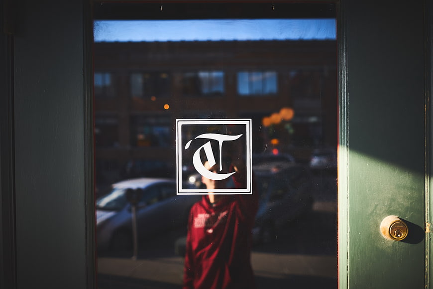 Man in Red Hoodie Reflected in Glass Door with Logo
