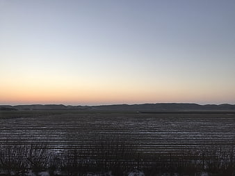 Serene coastal landscape with tidal flats and distant mountains at dusk