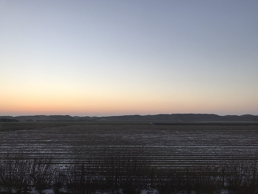 Serene coastal landscape with tidal flats and distant mountains at dusk
