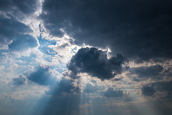 Dramatic sun rays breaking through dark storm clouds