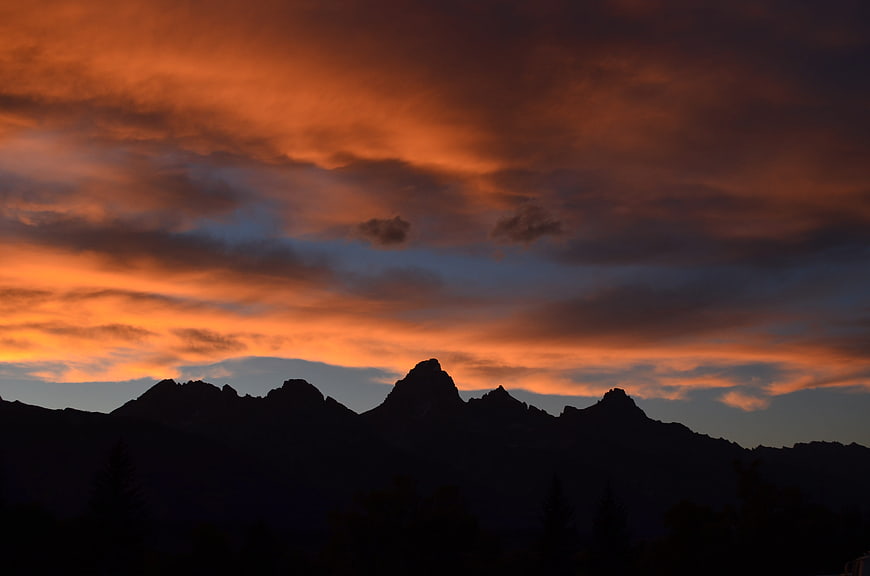 Dramatic orange sunset over dark mountain silhouette