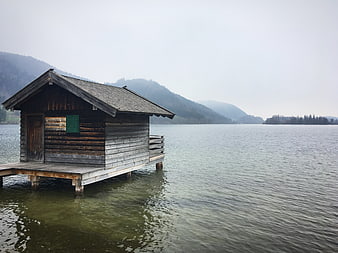 Rustic wooden boathouse on a misty lake with mountains
