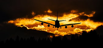 Silhouette of Airplane Landing Against Dramatic Sunset Sky