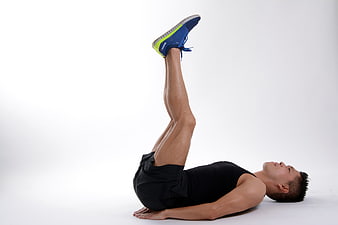 Man performing leg raise exercise on white studio background