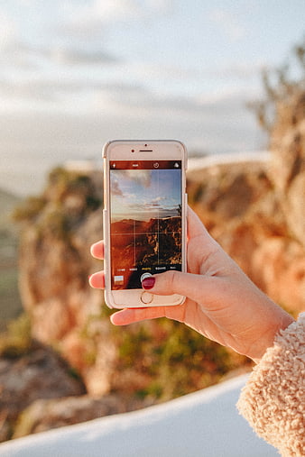 Woman taking landscape photo with smartphone at sunset