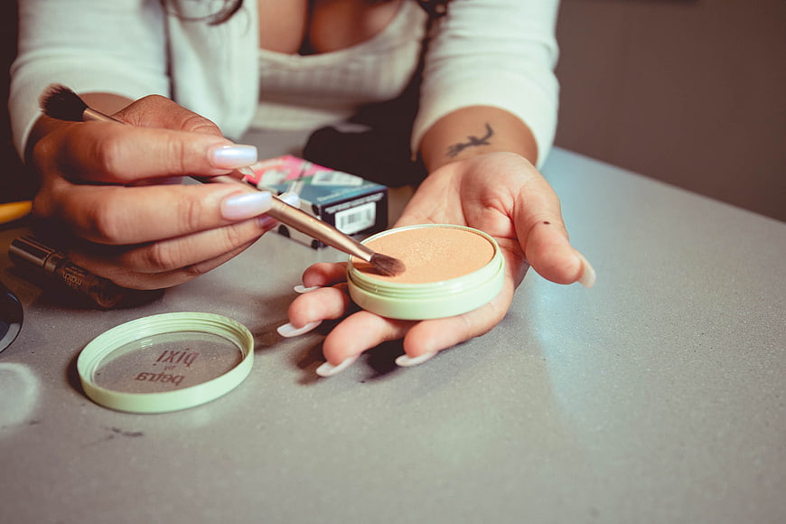 Woman applying makeup with brush and compact powder