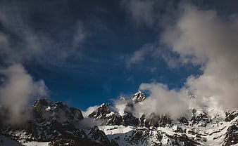 Snowy Mountain Peaks with Clouds and Blue Sky