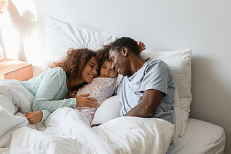 Happy African American Family Cuddling in Bed Together