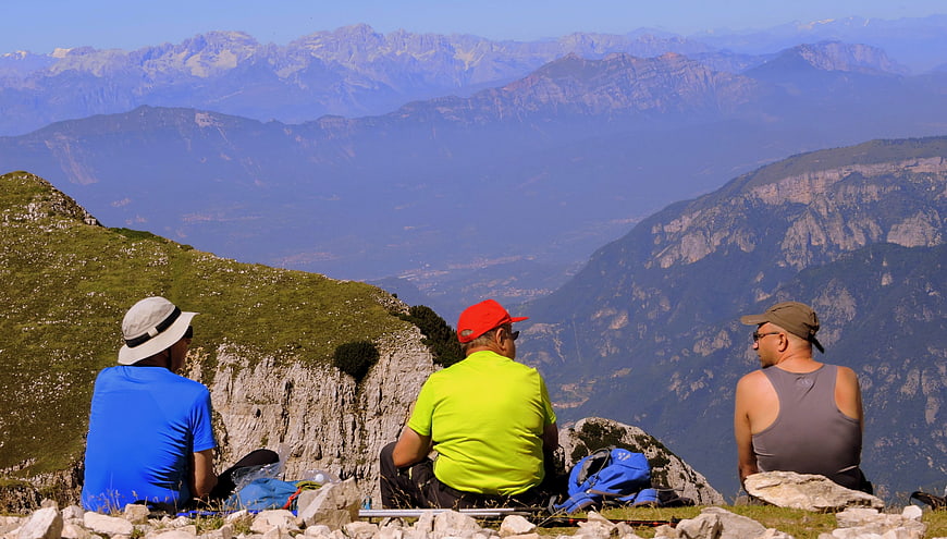 Three Hikers Resting on Mountain Summit with Panoramic View
