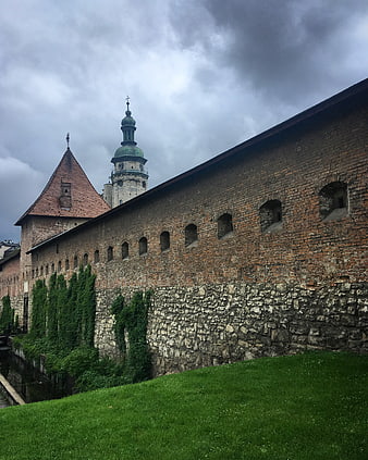 Medieval Fortress Wall with Church Tower Under Cloudy Sky
