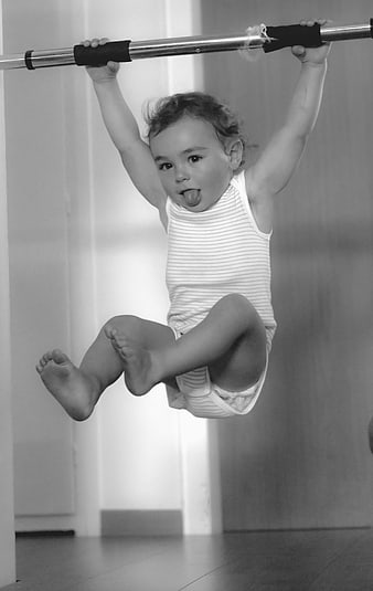 Toddler Hanging From Bar With Tongue Out