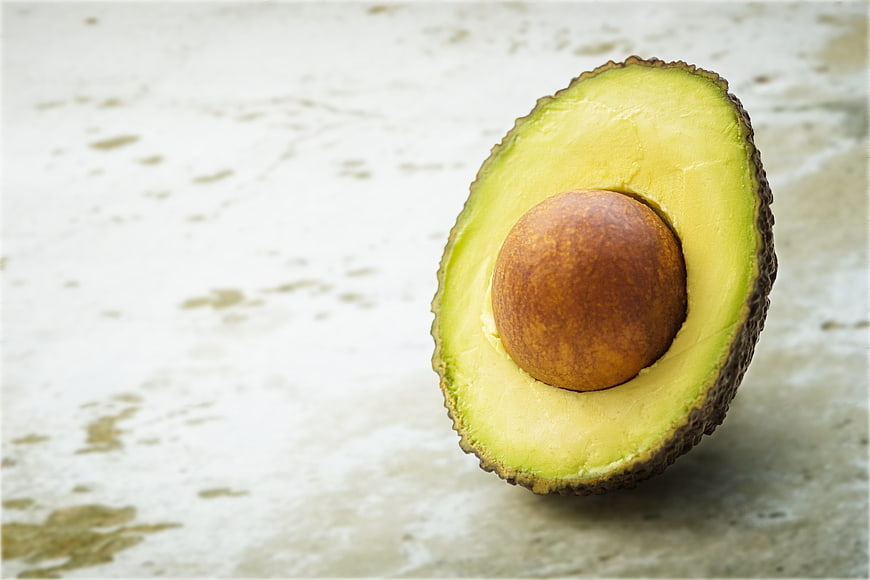 Fresh Halved Avocado with Pit on Textured Background