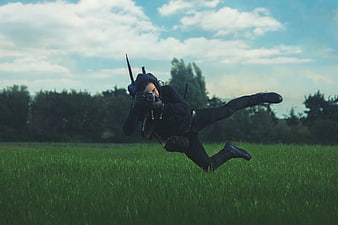 Man jumping in grassy field holding camera
