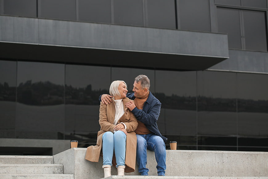 Happy Senior Couple Sitting on Concrete Steps in City