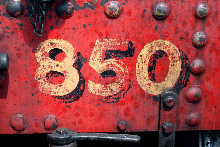 Vintage red metal plate with number 850 and rivets