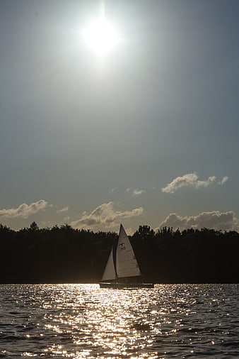 Sailboat Silhouette on Sparkling Lake at Sunset